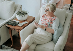 An older woman sitting in a chair holding a phone